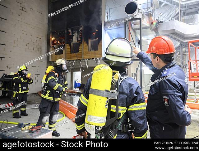 PRODUCTION - 10 October 2023, Lower Saxony, Brunswick: Firefighters extinguish a burning wooden façade during a research project at the Center for Fire Research...
