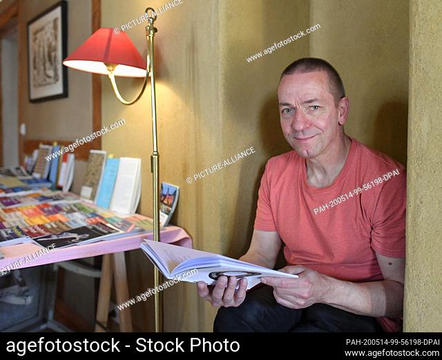 08 May 2020, Brandenburg, Joachimsthal: Gisbert Amm, owner of the Lyrikhaus in Joachimsthal, is sitting in his reading cafe with a book