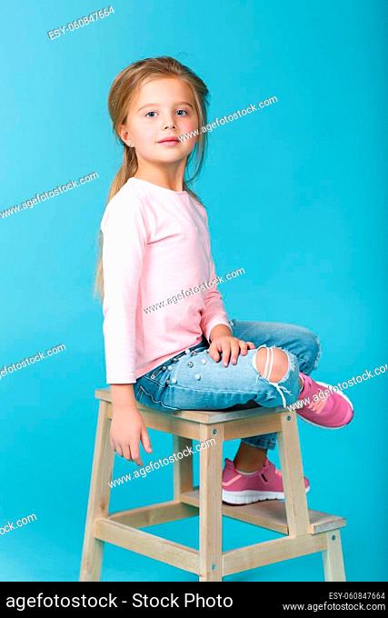 little beautiful girl in pink sweater and jeans posing in studio