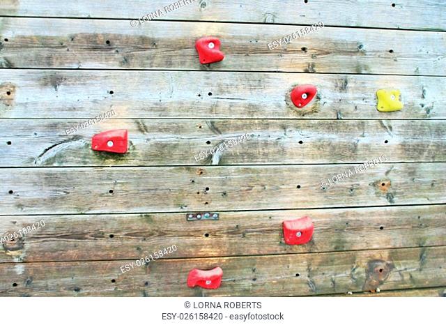 wooden climbing wall with bright colored foot holds