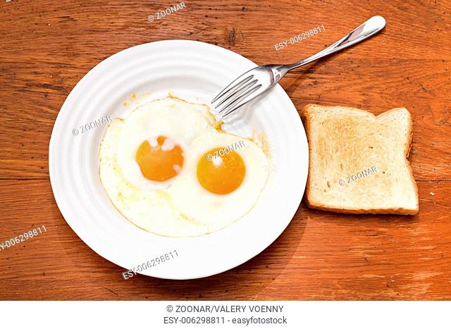 breakfast with two fried eggs in white plate