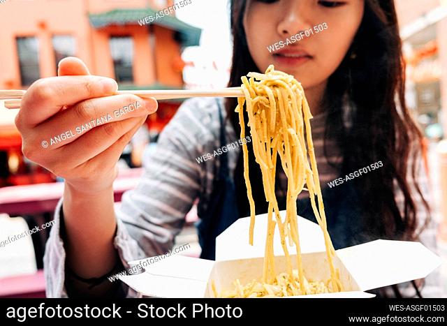 Woman holding noodles in chopsticks
