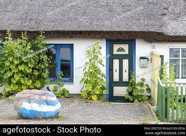 07 July 2020, Mecklenburg-Western Pomerania, Schaprode: View of an old front door and a thatched roof of a listed house. Photo: Stephan...