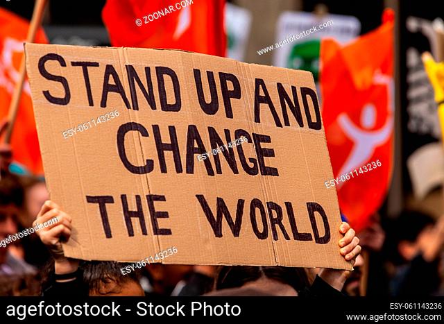 A cardboard sign is seen close up, saying stand up and change the world, as eco-activists march for the environment on a street in Montreal, Canada