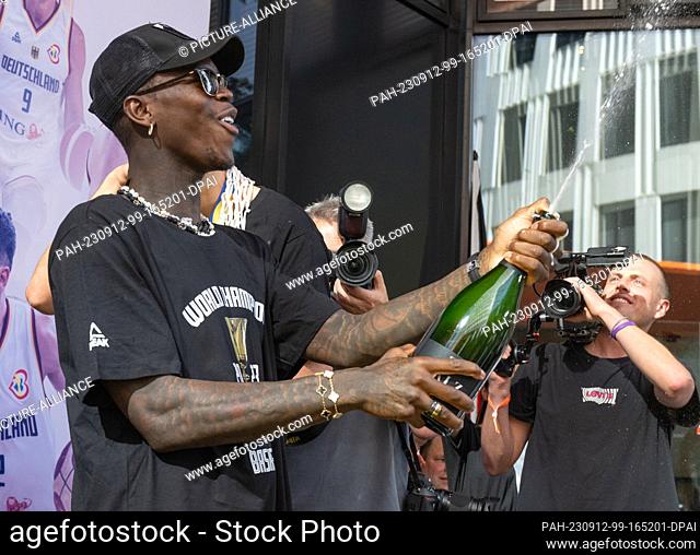 12 September 2023, Hesse, Frankfurt/Main: Dennis Schröder, captain of the national basketball team, splashes the press and public with champagne at the team's...