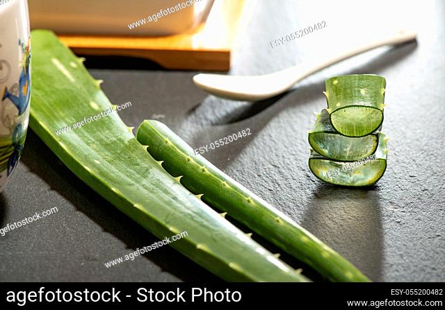 Aloe vera slices on dark background. Health and beauty concept. Closeup aloe pieces and spoon on backlight