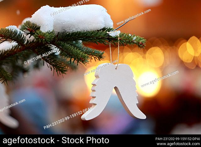 02 December 2023, Saxony-Anhalt, Quedlinburg: Christmas tree decorations hang on a Christmas tree at a small Christmas market in a courtyard in the Advent town...