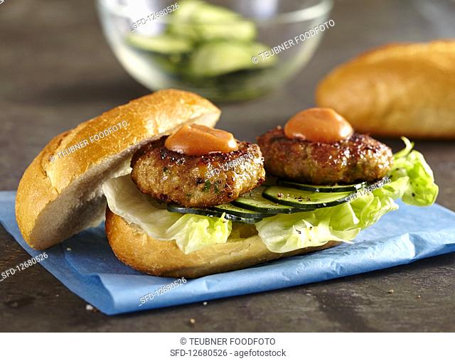 Meatball sandwich with marinated cucumber, lettuce leaves and ketchup