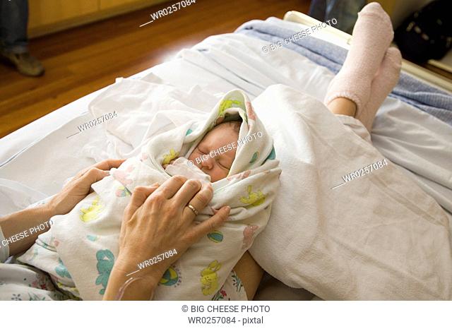 Mother swaddling newborn infant