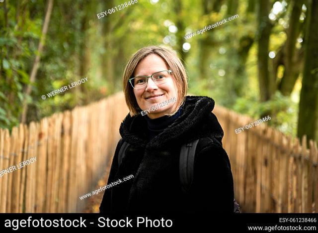 Attractive thirty year old white woman posing in a black furry coat, looking playful, Jette, Belgium