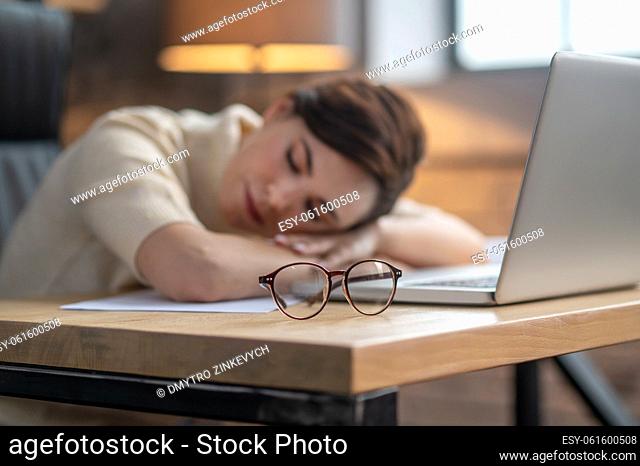 Tired and sleepy. A dark-haired woman napping at the laptop after a hard day