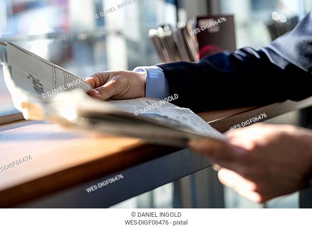 Close-up of businessman reading newspaper at the window in a cafe
