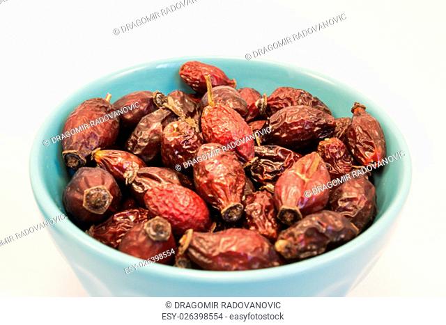 Dry rosehips in bowl on white background