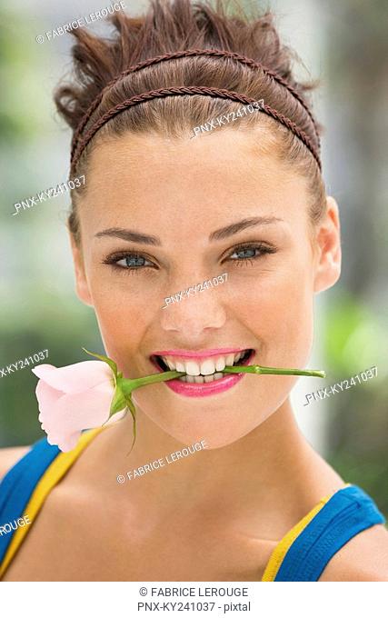 Fashion model holding rose between her teeth