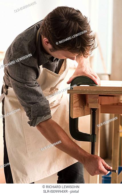 Carpenter adjusting clamp in workshop