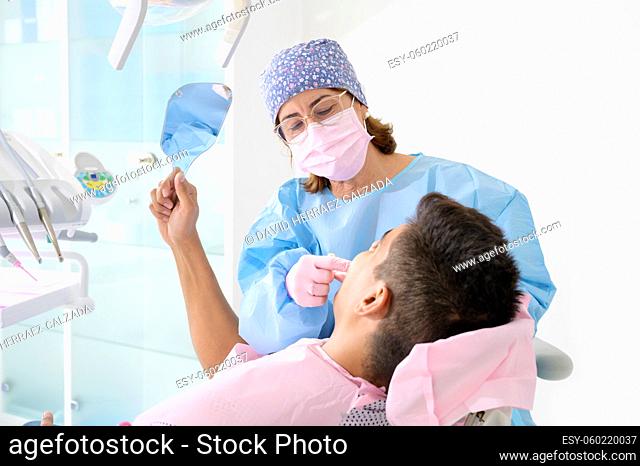 Patient looking teeth in mirror at dental clinic. High quality photo