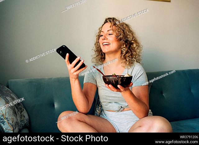 young woman, smiling, sofa, breakfast, voice message