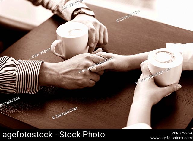 Hands on the table holding cups of coffee