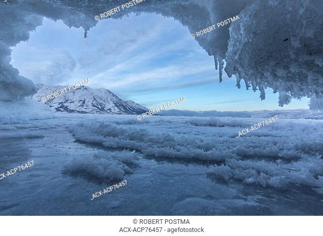 Kluane Lake after the ice has partially covered the lake. Sheep Mountainis in the distance in the early morning hours seen through a small ice cave