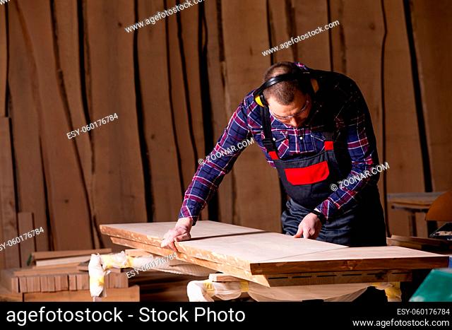 Male carpenter preparing for sanding the board in the factory