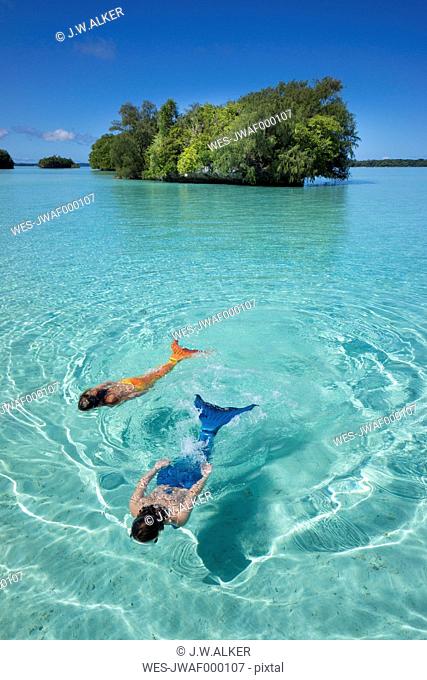 Palau, two young women in mermaid costume swimming in a lagoon