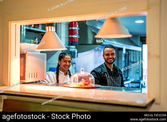 Smiling chef and trainee in commercial kitchen at restaurant