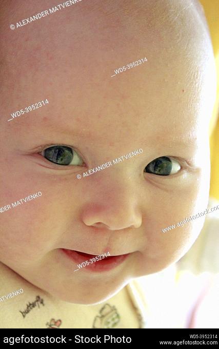 Portrait of smiling baby with blue eyes. Newborn child looking at mother. Face of newborn baby close up