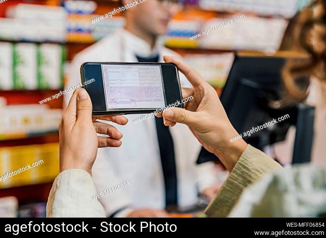 Hand of customer using smart phone for prescription in chemist store