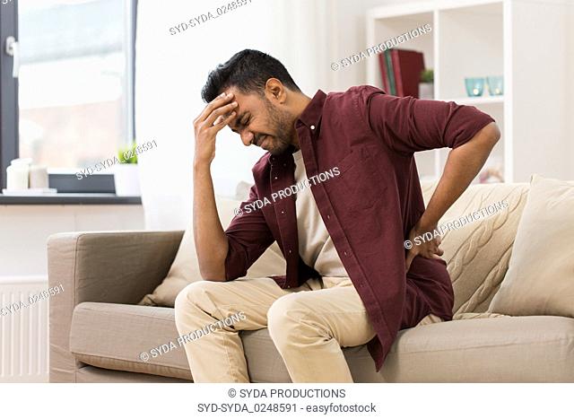unhappy man suffering from backache at home