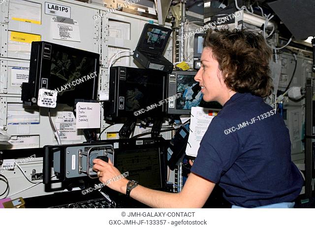 Astronaut Ellen Ochoa, STS-110 mission specialist, works the controls of the Canadarm2 in the Destiny laboratory on the International Space Station (ISS)