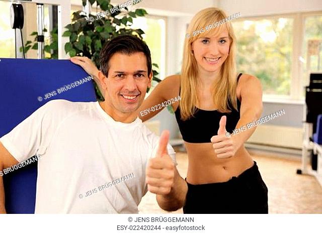 Attractive blonde woman and her trainer in a gym