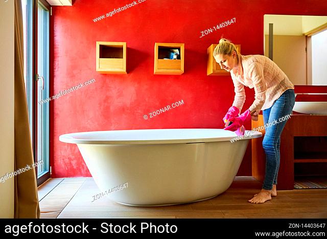 Reinigungskraft oder Putzfrau reinigt eine Badewanne beim Frühjahrsputz