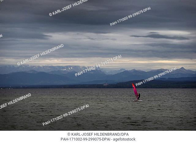 A sail boarder can be seen in front of the alpine panorama under neath thick clouds on the Ammer Lake near Inning, Germany, 02 October 2017