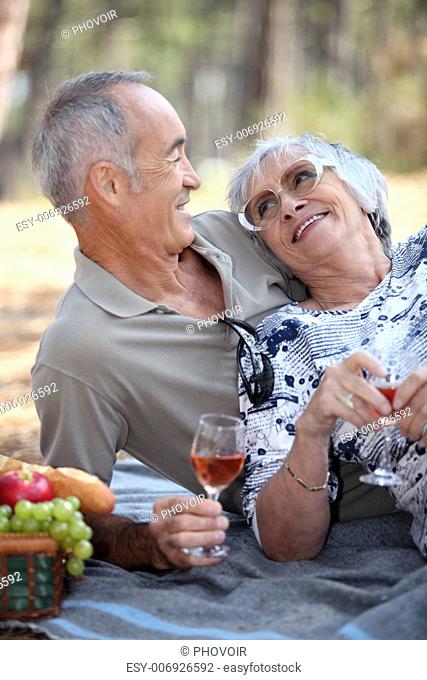 old couple taking a picnic beside trees
