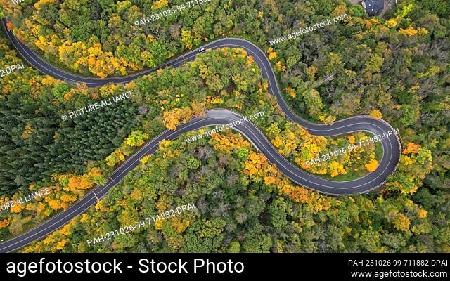 21 October 2023, Saxony-Anhalt, Blankenburg: The forests in the Harz Mountains near Blankenburg are colorful in autumn. A car drives in serpentines from...