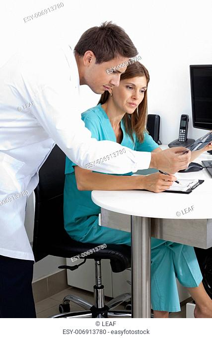Male dentist and assistant checking X-ray at dental clinic