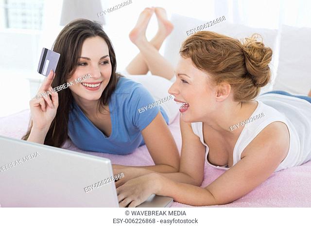 Female friends doing online shopping in bed