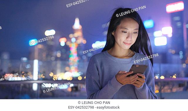 Asian Woman look at smart phone in city at night