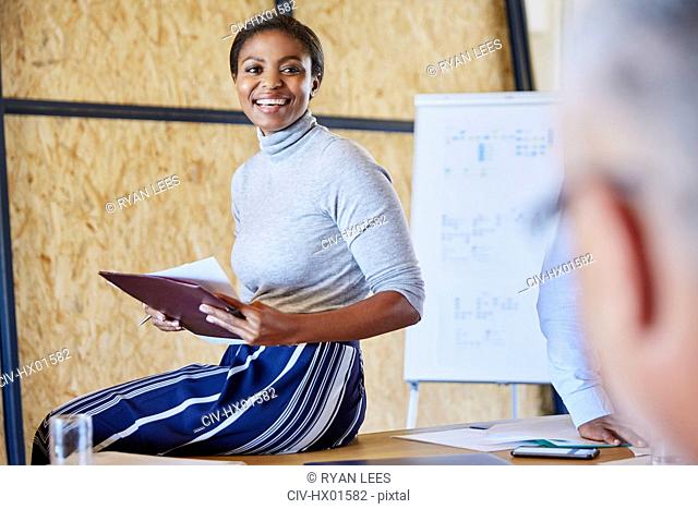 Smiling businesswoman with paperwork in meeting