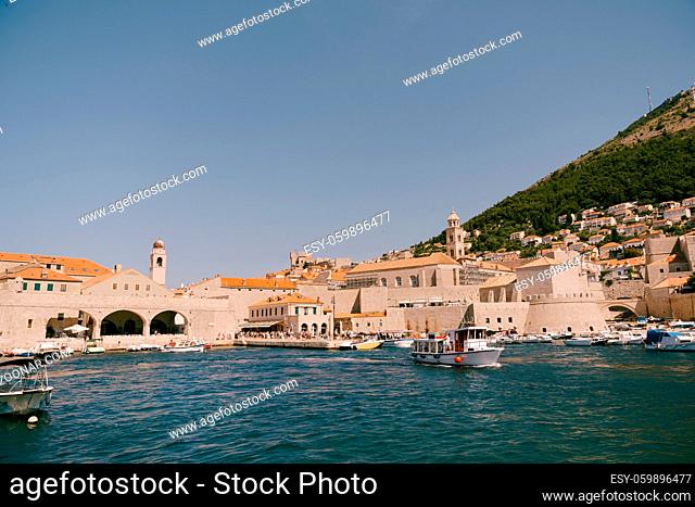 A ship with tourists goes on an excursion. The old port harbor is porporela, near the walls of the old town of Dubrovnik, Croatia