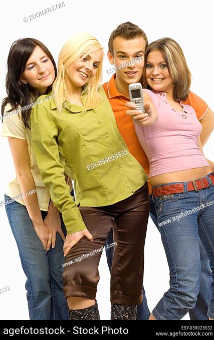 Three young woman and a man. Woman on the right is holding mobile phone and making the picture to the group. Isolated on white in studio