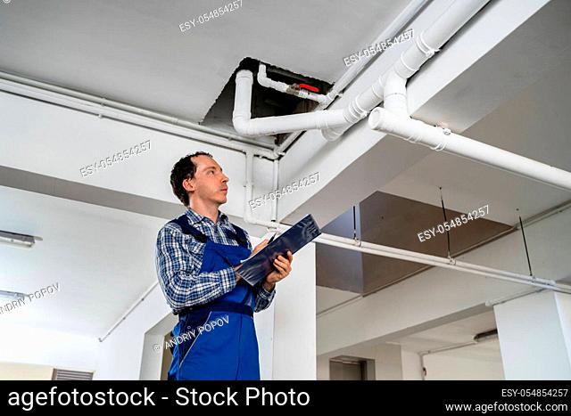 Male Worker Inspecting Pipes In Residential Building