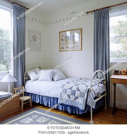 Blue patchwork quilt and white linen on white bed in blue+white themed bedroom