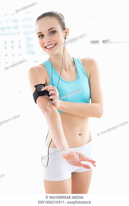 Sporty smiling woman pressing a button on mp3 player