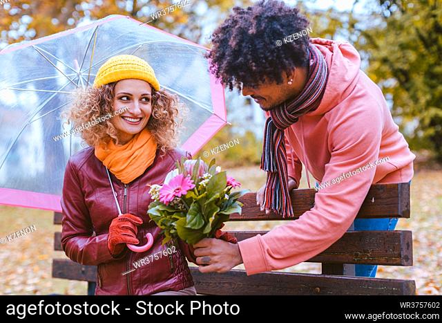 Man surprising his wife with a bouquet of flowers on a drizzly fall day to bring joy to her life