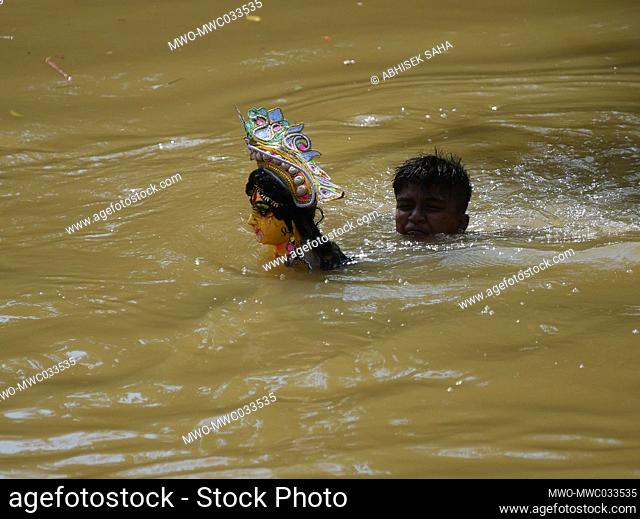 A child holds the head of an idol of the goddess Durga during an immersion ceremony for Dashami, the last day of the Durga Puja festival