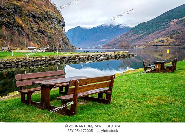 Wooden benches on a lawn in resting picnic area on the shore of a fjord in small village Flam, Norway