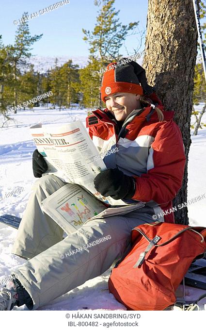 Kvinna på skidtur sitter och läser dagstidning MR\\Sälen, Dalarna\\\\©Håkan Sandbring / sydpol.com / IBL bildbyrä