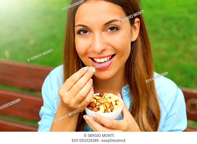 Close up of young woman eating mixed nuts in the park