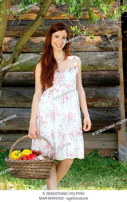 una donna sorridente con un cesto di verdura in un giardino